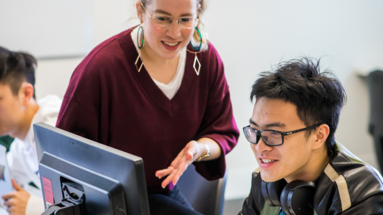 Student and teacher discussing work in front of computer UNSW