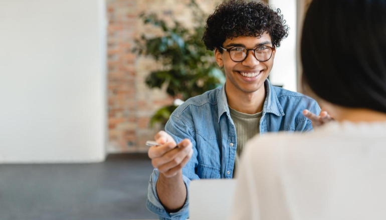 student smiling behind laptop