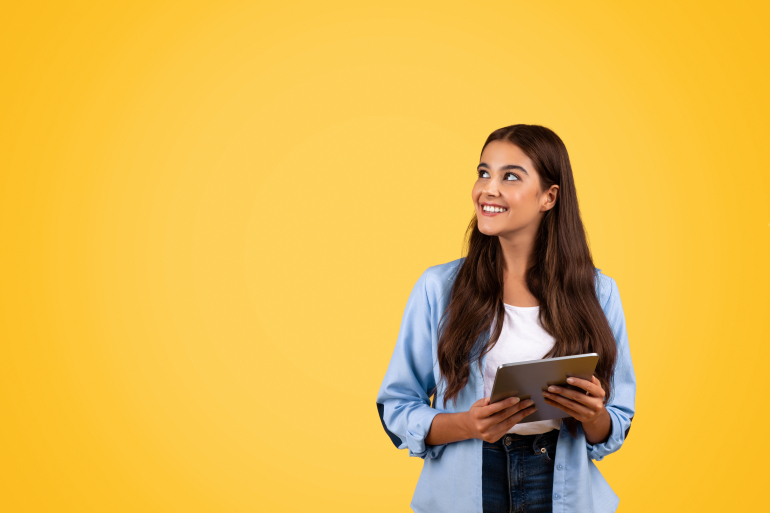 Female with long dark hair holding a tablet device and smiling to her right