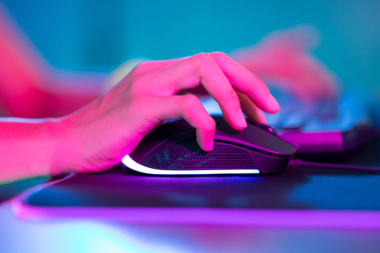 Hand on computer mouse in dimly lit room