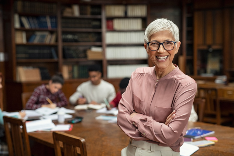 Teacher facing camera with students studying in the background