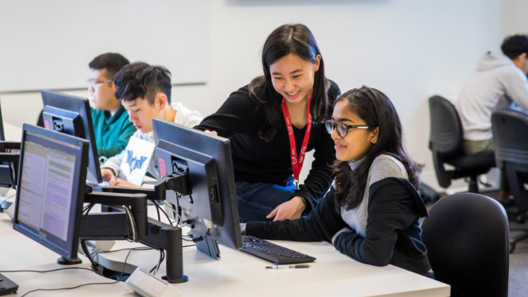 Student and teacher sitting at computer and talking UNSW