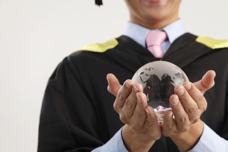 Graduate holding a globe in his hands