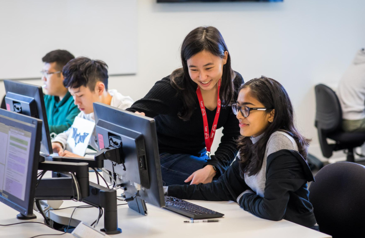Teacher and students looking at computer and smiling