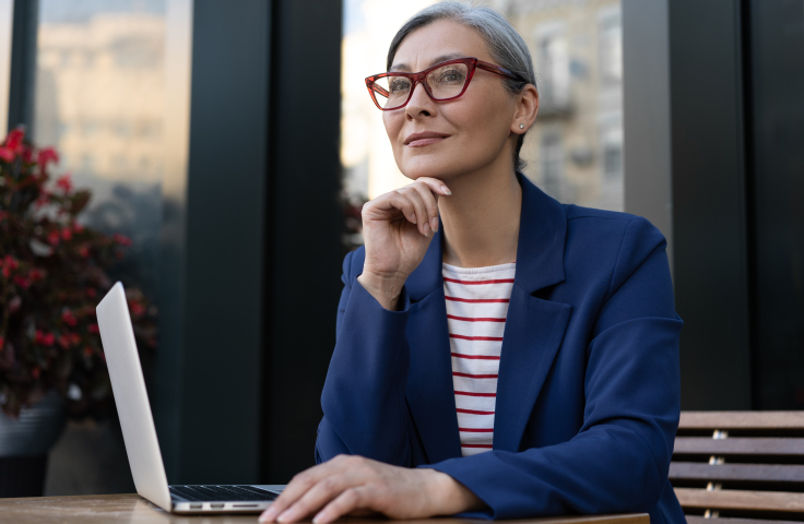 Lady with glasses pondering with laptop in front of her