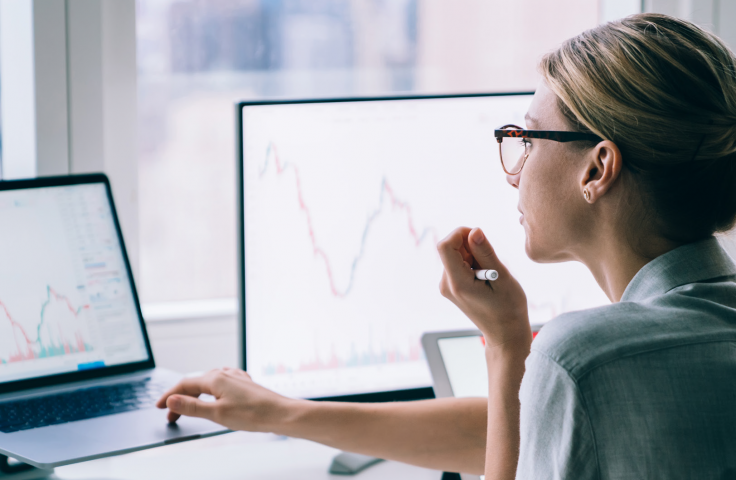 Woman looking at two screens with graphs