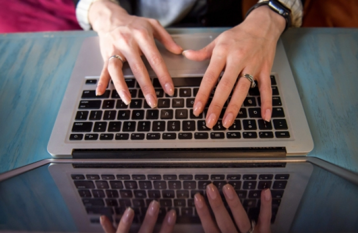 Hands typing on laptop